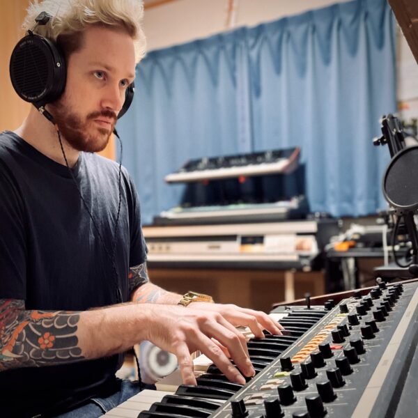 Marcus D playing his Korg Trident synthesizer wearing Audeze headphones